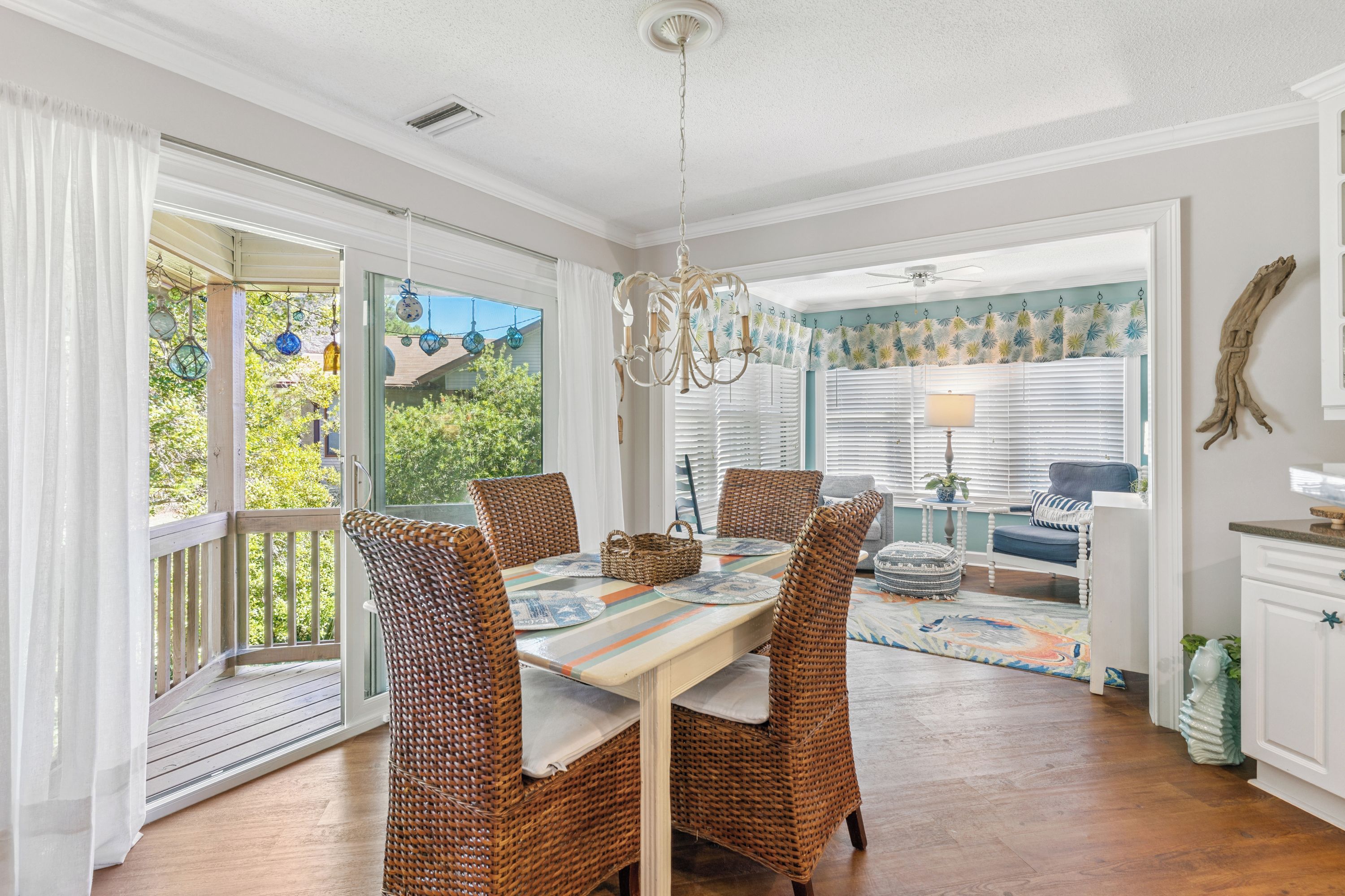 A dining area with wicker chairs, a table with placemats, and a view through a glass door to the outside.
