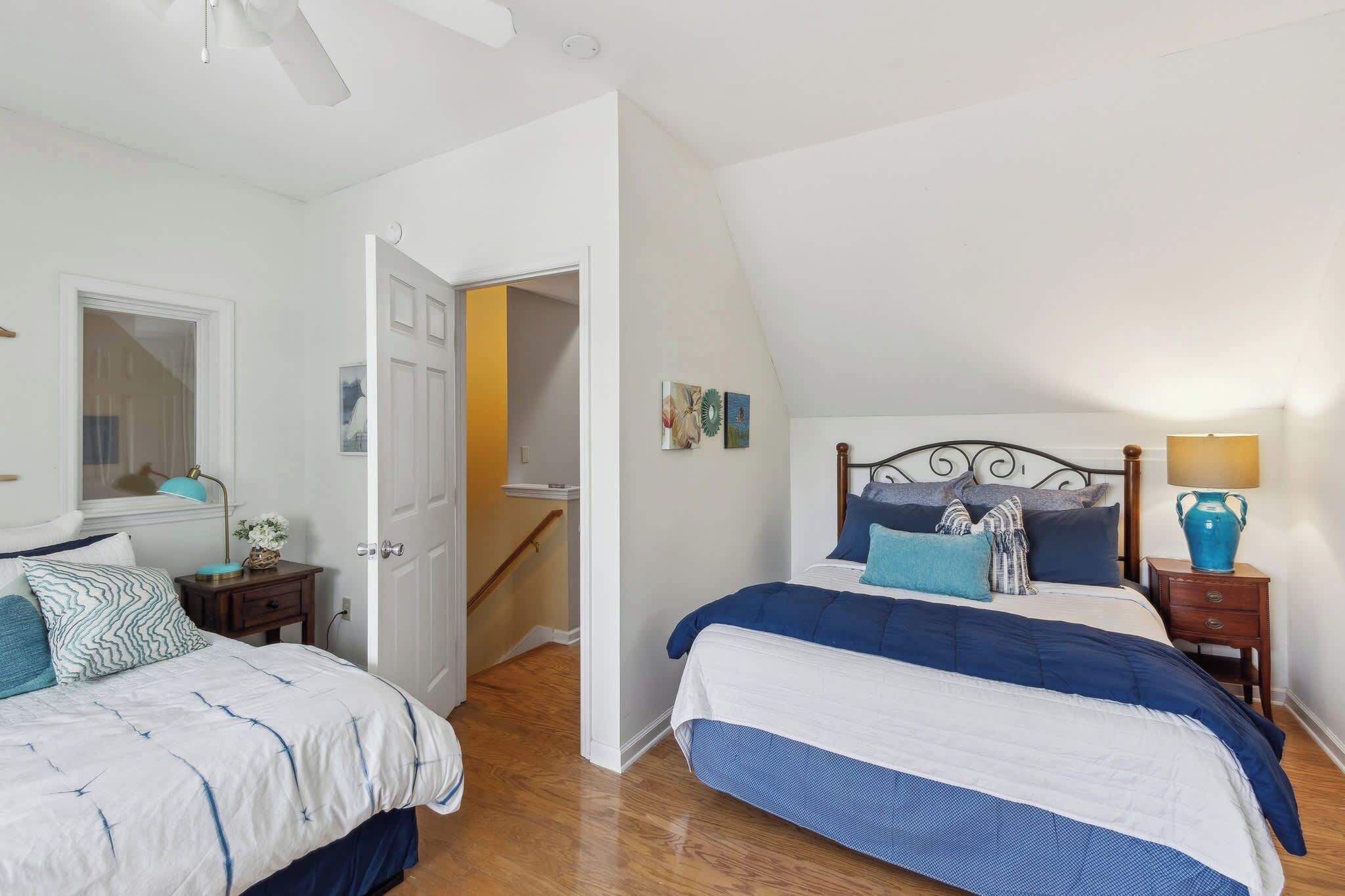 A bedroom with two beds, a staircase, and a door leading to another room.