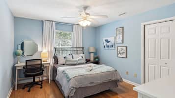 Un dormitorio con cama, escritorio, silla y ventilador de techo.