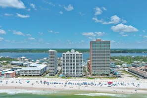 Un paisaje urbano costero con rascacielos, una playa con sombrillas y un puerto deportivo.