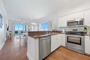 A modern kitchen with white cabinetry, stainless steel appliances, and a wooden island. - Gulf Front Condo with Private Balcony and Stunning Views, Sleeps 8, BEACHBALL PROPERTIES (Gulf Shores)