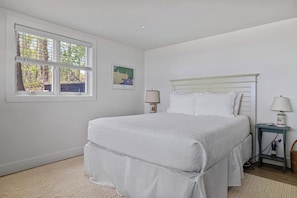 A bedroom with a bed, two bedside tables, a window, and a wall-mounted picture. - The Lake House | Private Beach • Sunsets • 6BR! (Bridgman)