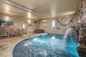 An indoor swimming pool with a stone wall, a hammock, and a poster on the wall. - Star of the Summit: 5 bedrooms, Private Indoor Pool, Stunning Views (Sevierville)