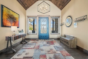 A reception area with a blue door, a bench, a console table with a lamp, a colorful rug, and a large painting. - Star of the Summit: 5 bedrooms, Private Indoor Pool, Stunning Views (Sevierville)