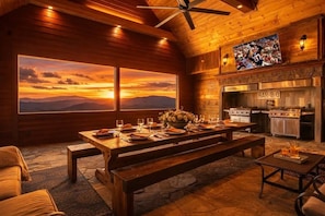 A cozy dining area with a large table set for two, a fireplace, and a television mounted above it. - Tennessee Whiskey: Sweeping Views, Indoor Pool, 9-hole Golf (Sevierville)