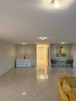 A spacious living area with a white cabinet, a yellow sofa, and a painting on the wall. - Luxurious 4-bedroom Apartment in Central Montreux (Montreux)