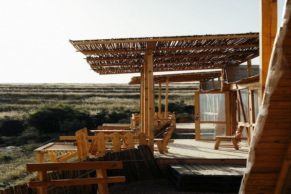 Una terraza de madera con asientos y una estructura de techo de paja.