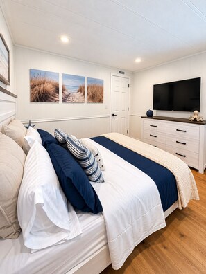 A bedroom with a bed, a television, and artwork on the wall. - Casita Azul - Pine Island Waterfront Retreat • Kayaks, Fishing & Outdoor Lounge (Saint James City)