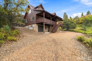 A two-story wooden cabin with a covered porch and a gravel driveway. - Elk Tracks Cabin in Scenic Location with Fire Pit (Alton)