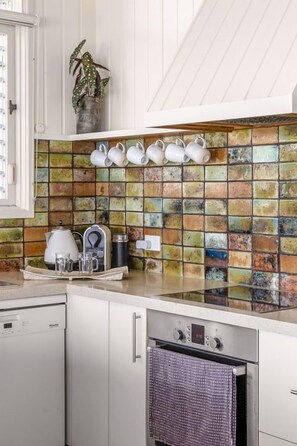 A kitchen with a tiled backsplash, a countertop with kitchenware, and a dishwasher.