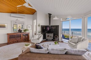 A spacious living room with a large window overlooking the ocean, a fireplace, and a cozy seating area.