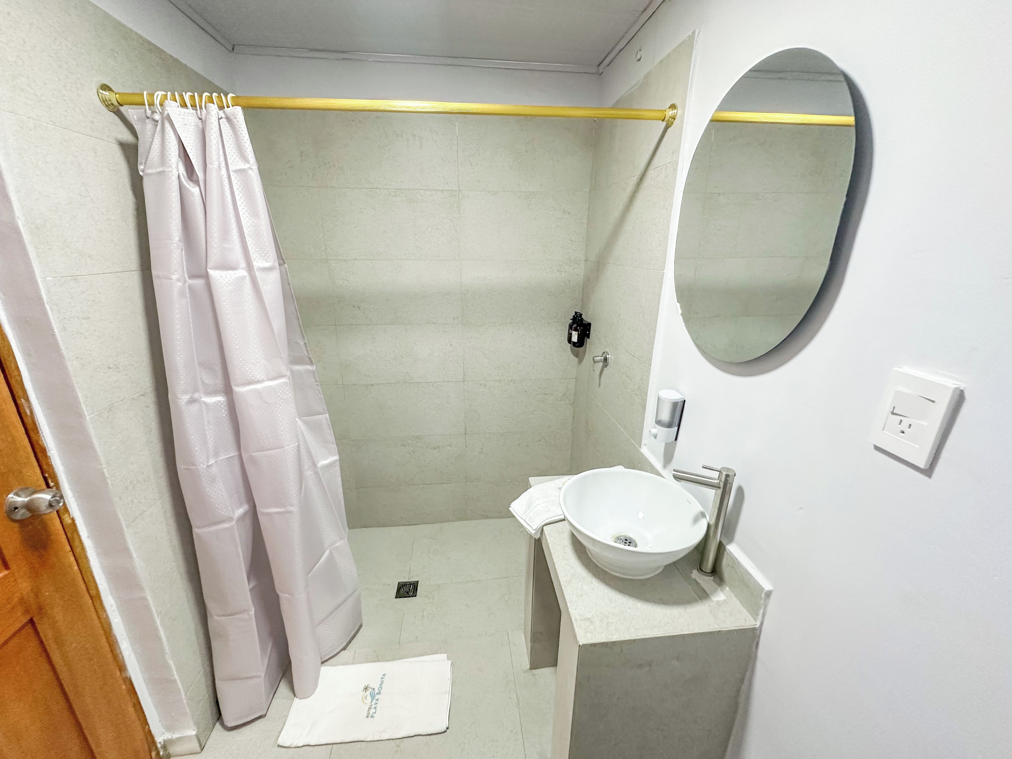 Un bagno con doccia, lavandino, specchio e asciugamano.