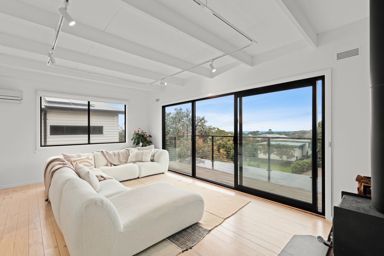 A modern living room with a sofa, large windows, and a view of the outdoors.