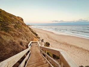 A wooden staircase leading down to a beach with a view of the ocean. - Jan Juc beach retreat: gentle 5 min walk to beach, ocean views and fire pit. (Jan Juc)