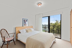 A bedroom with a bed, a chair, a picture on the wall, and a balcony with a view. - Jan Juc beach retreat: gentle 5 min walk to beach, ocean views and fire pit. (Jan Juc)