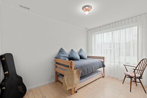 A bedroom with a bed, a guitar, a chair, and a window with curtains. - Jan Juc beach retreat: gentle 5 min walk to beach, ocean views and fire pit. (Jan Juc)