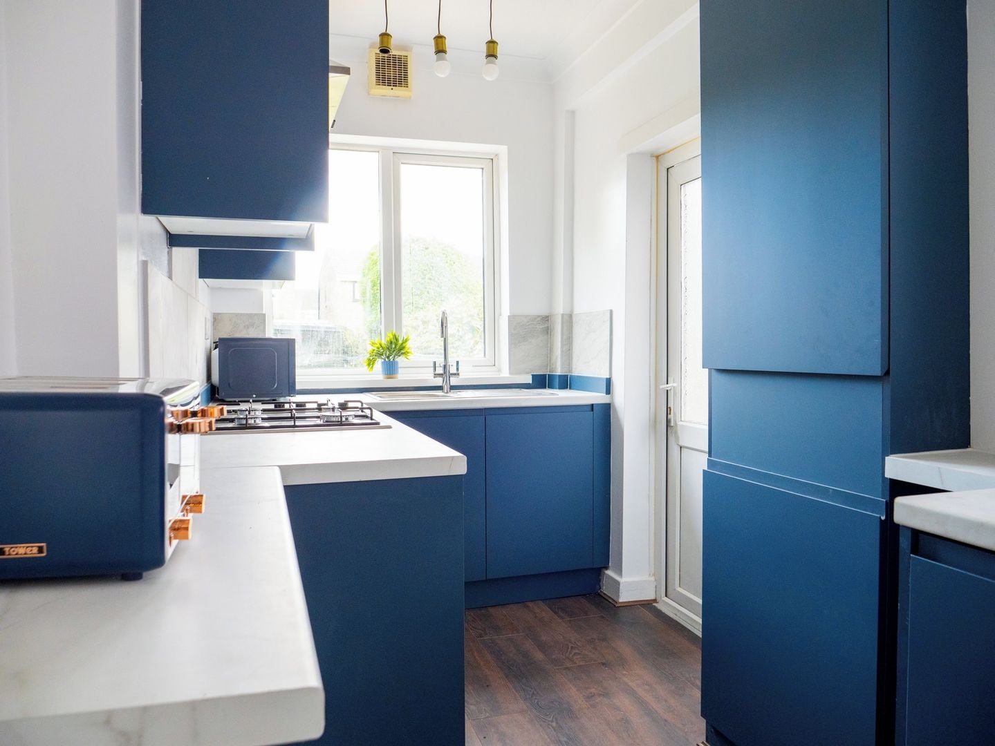 A modern kitchen with blue cabinets, a white countertop, and a built-in stove.