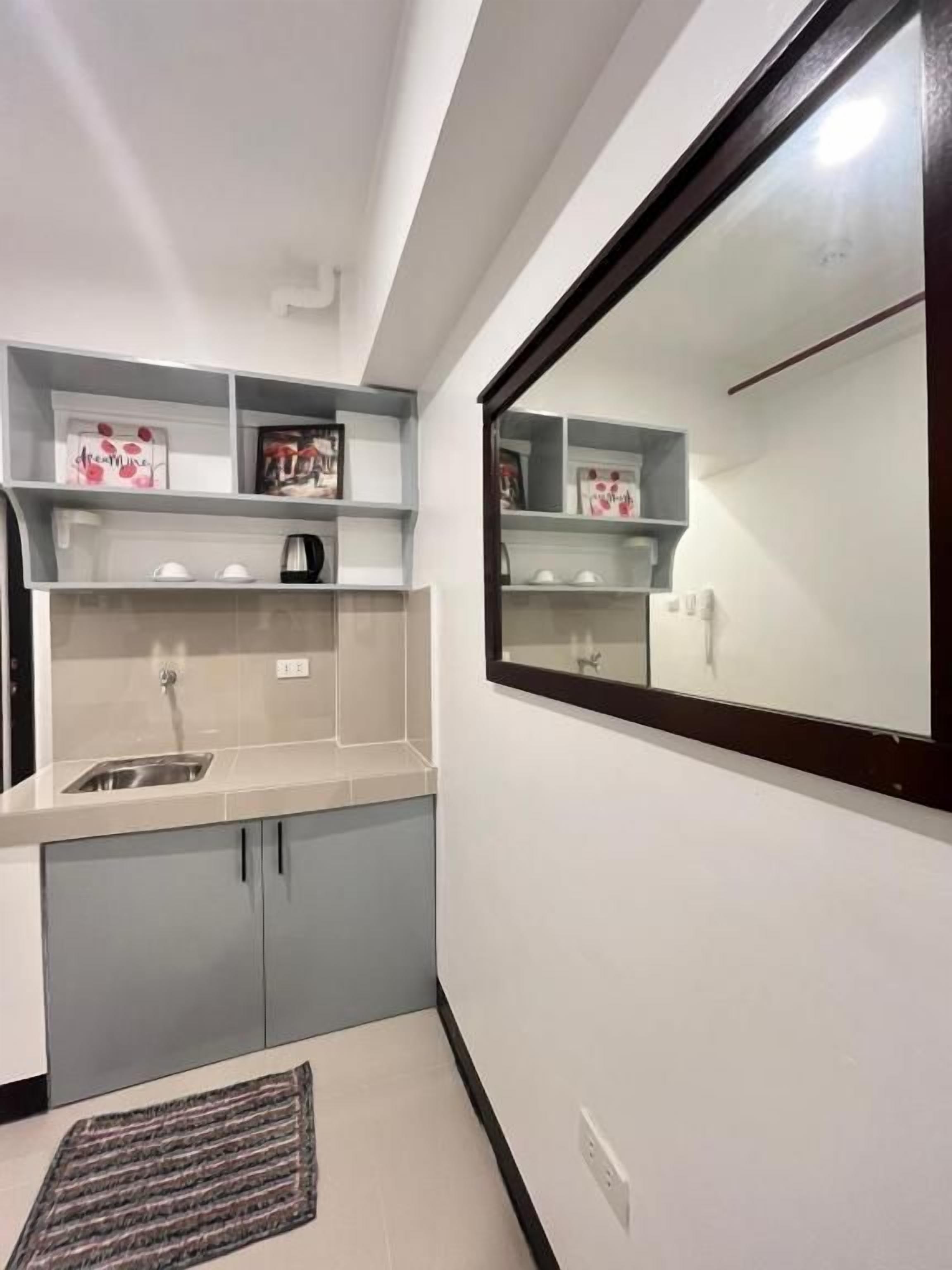 A compact kitchen with a built-in sink, a microwave, and a small countertop. There are cabinets below the countertop and a rug on the floor.