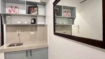 A compact kitchen with a built-in sink, a microwave, and a small countertop. There are cabinets below the countertop and a rug on the floor.