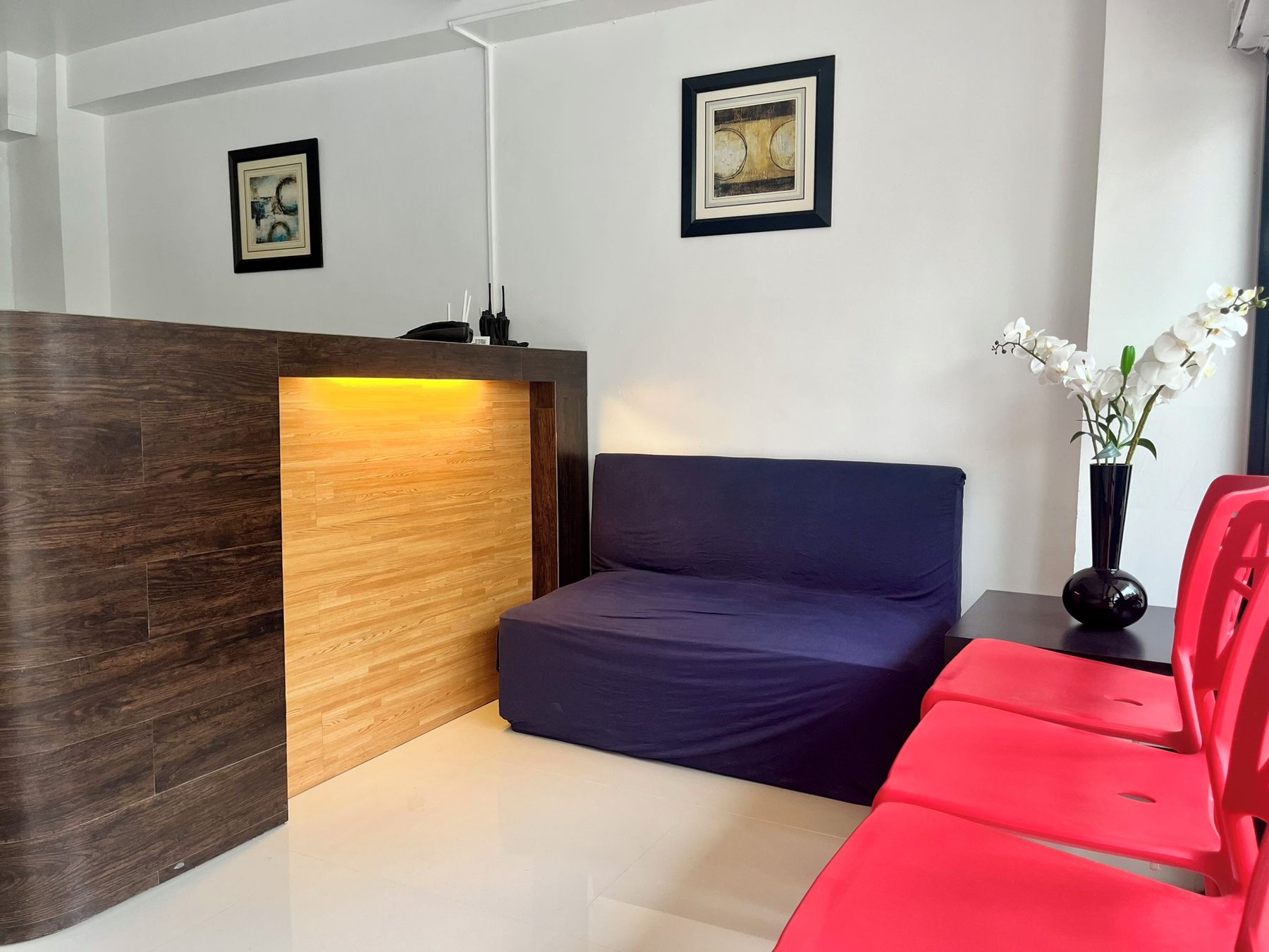 A modern hotel room with a reception desk, a blue sofa, and a red chair.