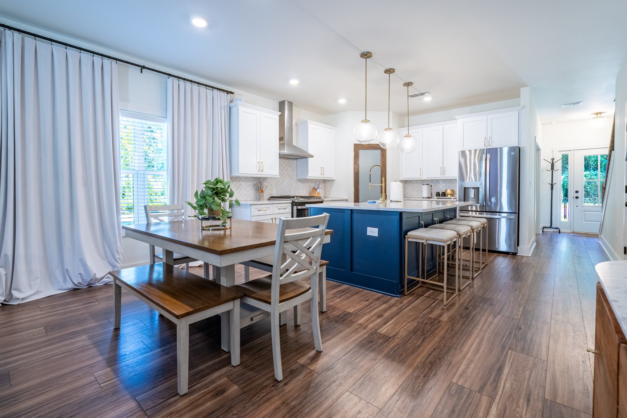 A modern kitchen with a central island, white cabinetry, and a stainless steel refrigerator.