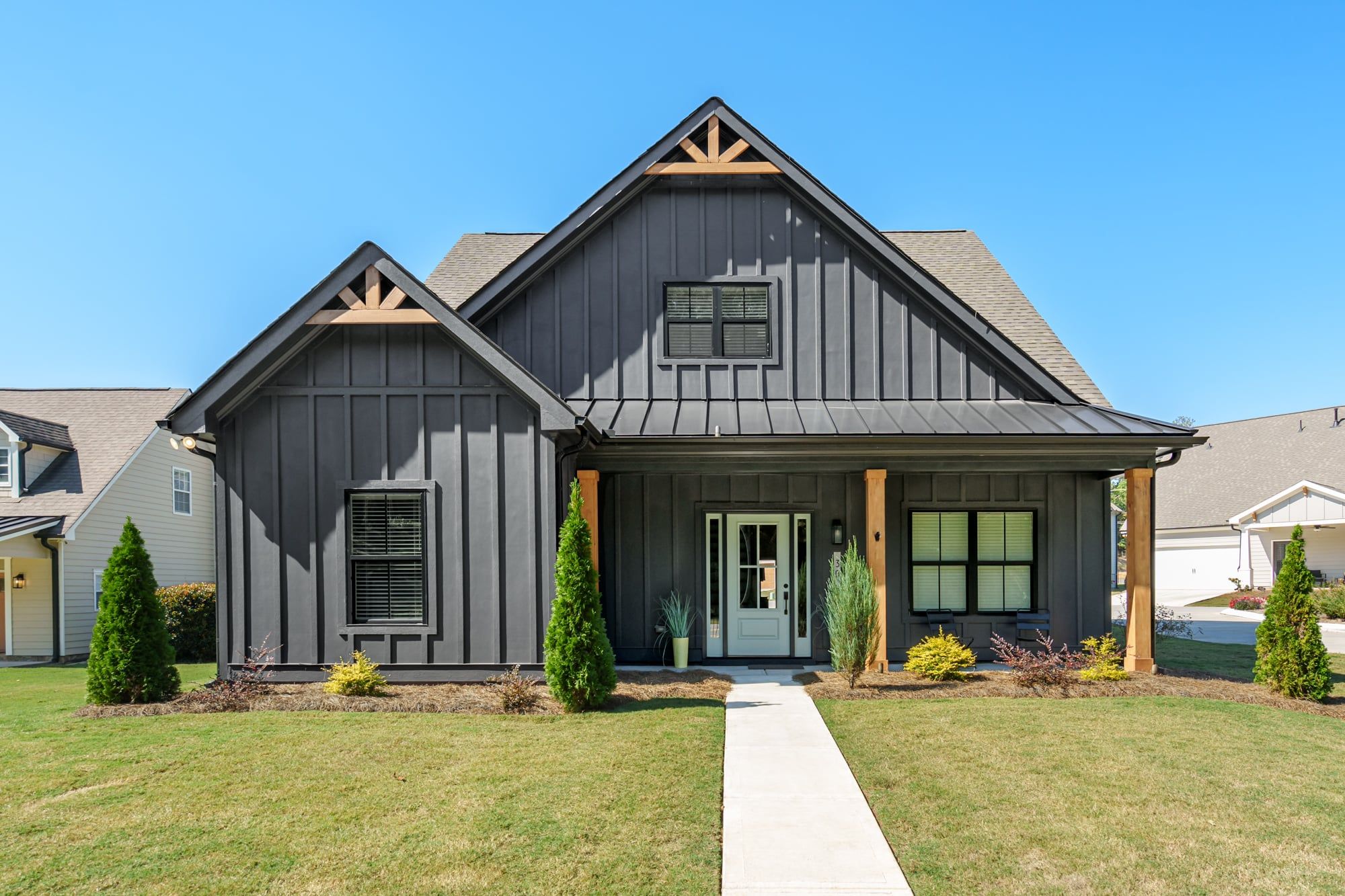 A two-story house with a front porch, a central door, and a small attached garage.