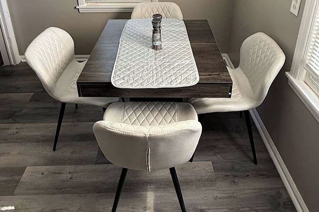 Un comedor con una mesa, cuatro sillas y un salero.