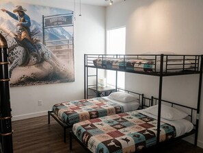 Habitación con literas, un mural temático del oeste, una ventana y una mesita.