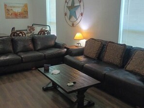 Ein Wohnzimmer mit einem Ecksofa, einem Couchtisch und einer Lampe.