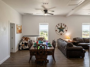Ein großzügiger Wohnbereich mit Esstisch, Ledersofas und einem Texas-Wappen an der Wand.