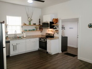 A modern kitchen with white cabinets, a stainless steel oven, a microwave, and a black refrigerator. - Stockyards Station: 4 Min to Stockyards! Sleeps 10 (Fort Worth)