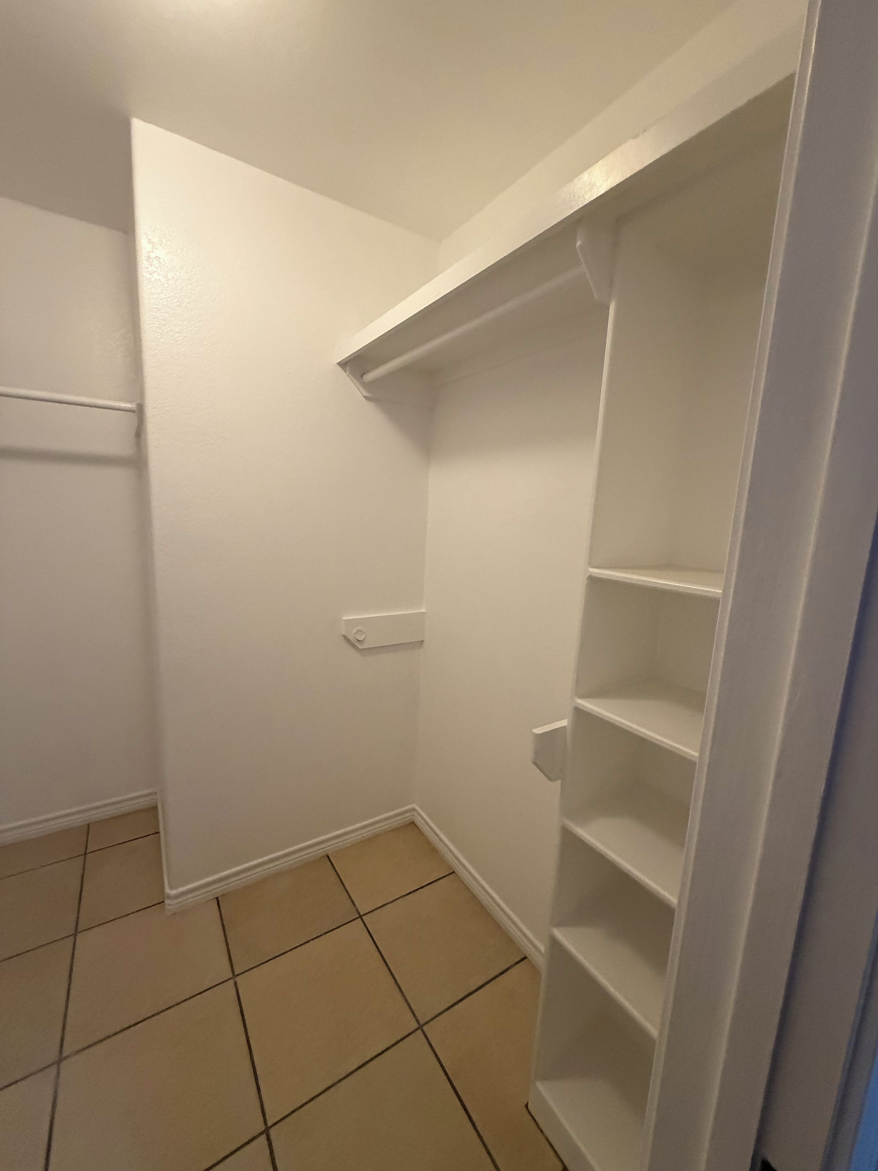 A corner of a room with a white door, a white wall, and a white shelving unit.