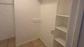 A corner of a room with a white door, a white wall, and a white shelving unit.