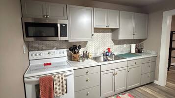 A kitchen with white cabinets, a microwave, a stove, and a ceiling fan.
