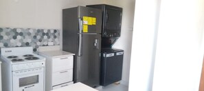 A compact kitchen with a white stove, a stainless steel refrigerator, and a black coffee maker. - Cozy 1-bedroom studio  apartment near  Bridgetown with AC Opp Sea, Beach, bars! (Bridgetown)