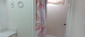 A bathroom with a toilet, a sink, and a shower curtain with a floral pattern. - Cozy 1-bedroom studio  apartment near  Bridgetown with AC Opp Sea, Beach, bars! (Bridgetown)