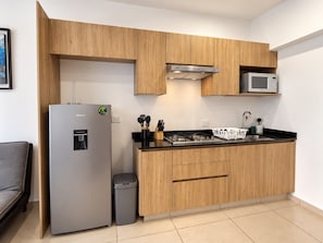 A modern kitchen with wooden cabinets, a stainless steel refrigerator, a microwave, and a gas stove. - New Listing (Zapopan)