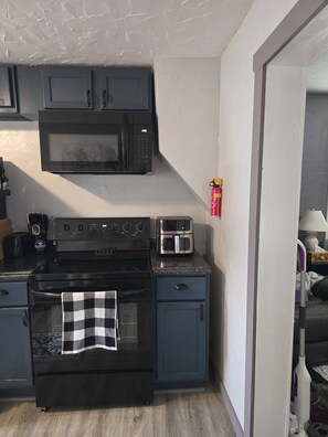 A compact kitchen with a microwave, stove, and toaster.