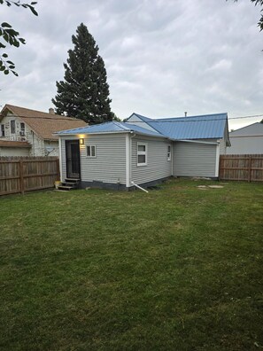 Une maison de plain-pied avec un toit bleu et un petit porche à l’avant.