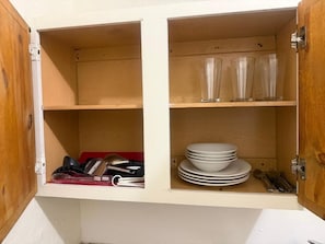 A kitchen cabinet with shelves containing dishes and utensils. - Downtown Purple Apartment (Phoenix)