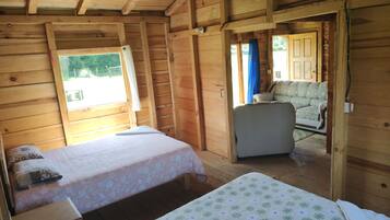 A wooden cabin with two beds, a sofa, and a window.