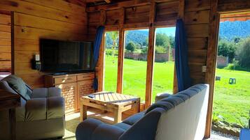 A wooden cabin interior with a TV, sofa, and a table.