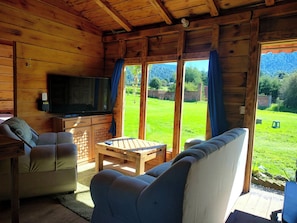Et interiør af en træhytte med TV, sofa og bord.