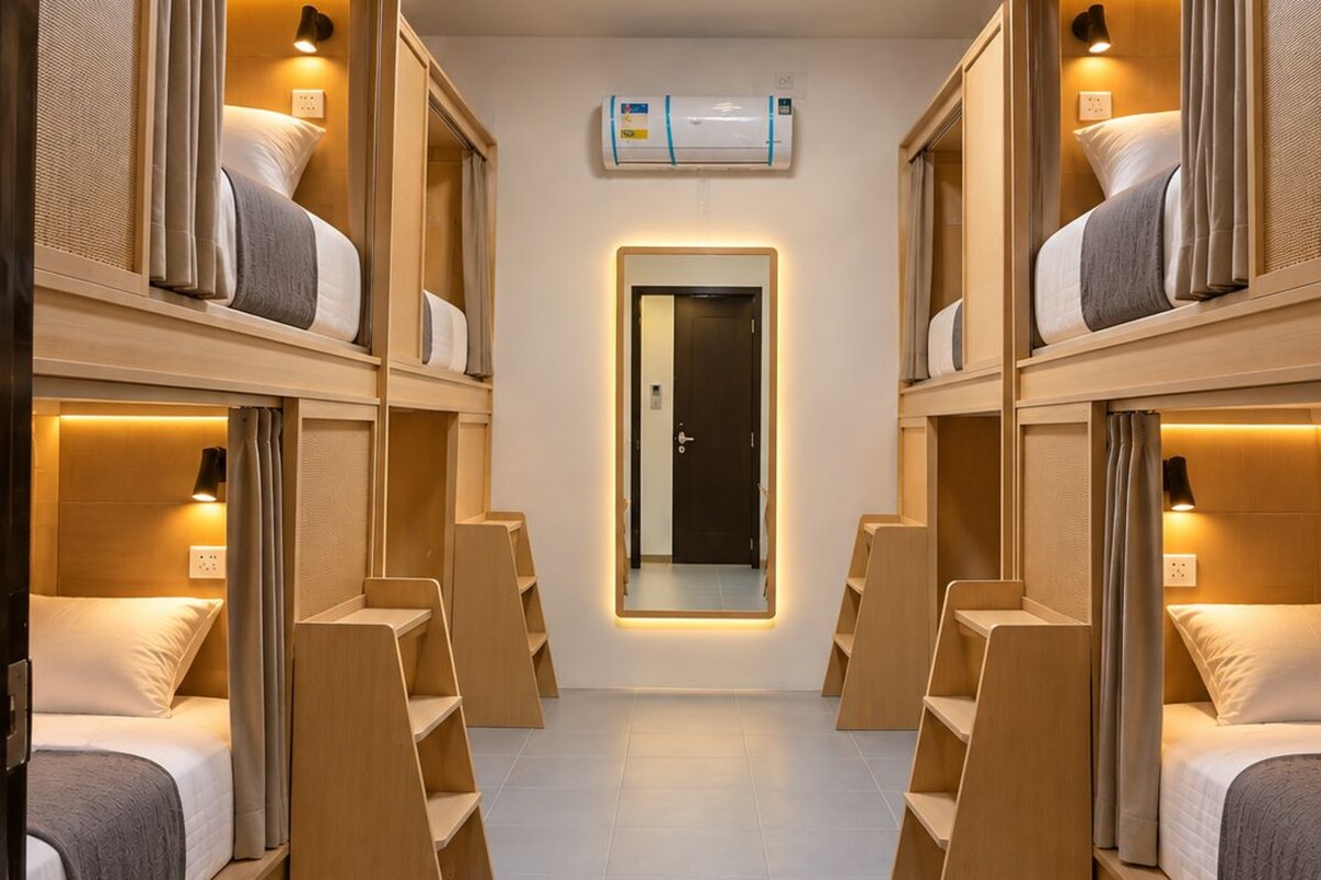 A hotel room with bunk beds, a central door, and a ceiling-mounted air conditioning unit.
