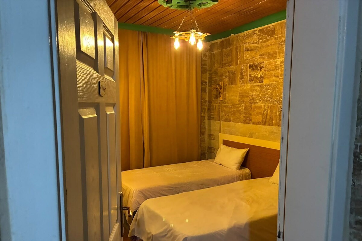 Habitació amb dos llits, sostre de fusta i paret de pedra.