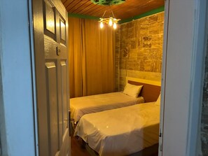 Habitació amb dos llits, sostre de fusta i paret de pedra.
