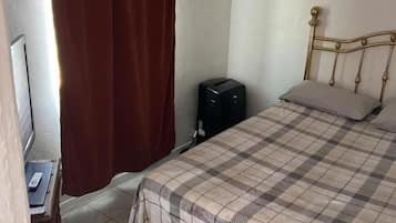 Un dormitorio con cama, escritorio y televisión.