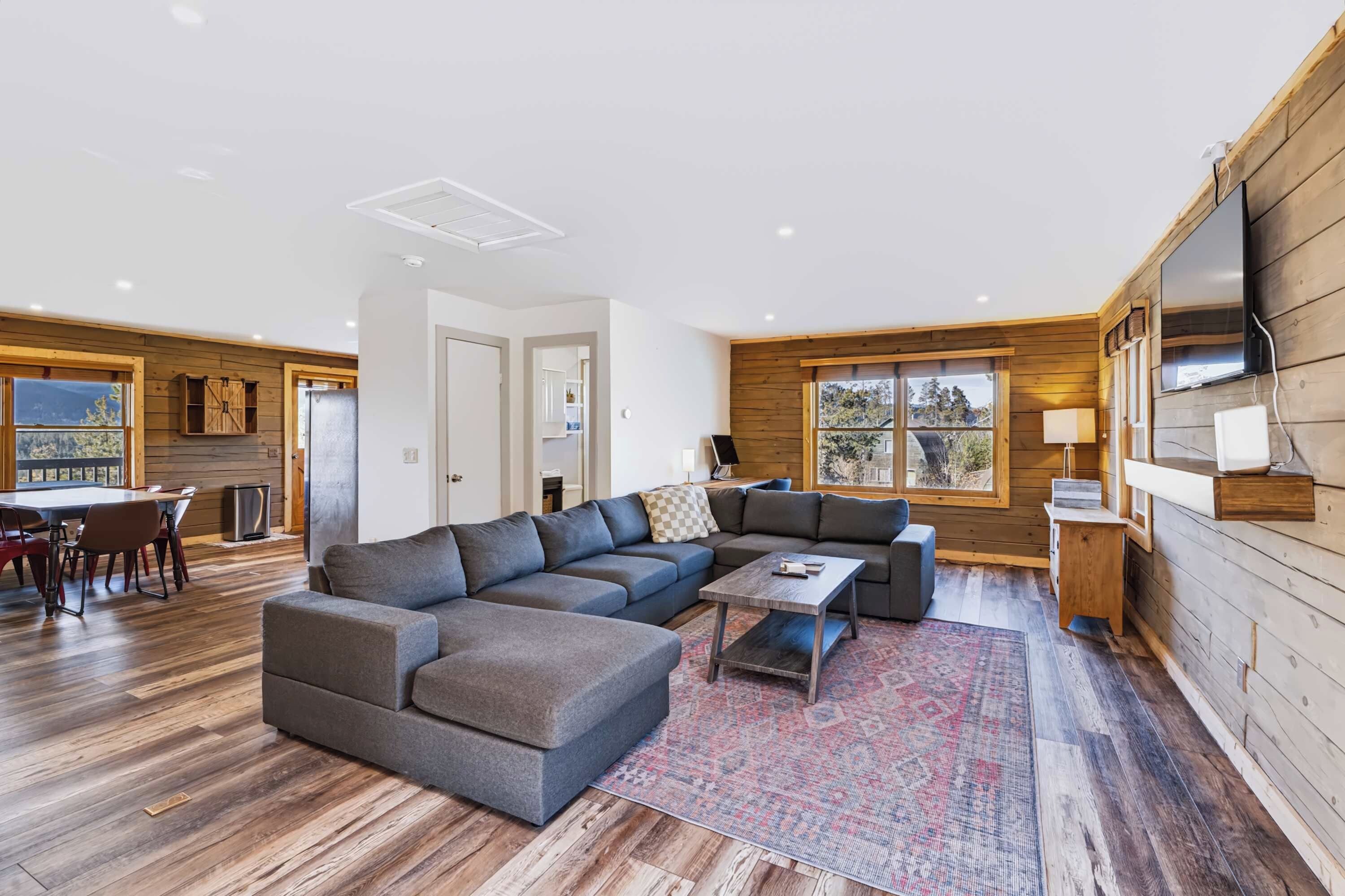A modern living room with a sectional sofa, a coffee table, and a TV mounted on the wall.