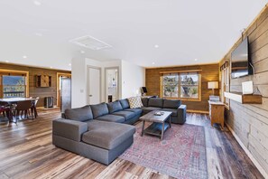 Una sala moderna con un sofá modular, una mesa de centro y un televisor montado en la pared.