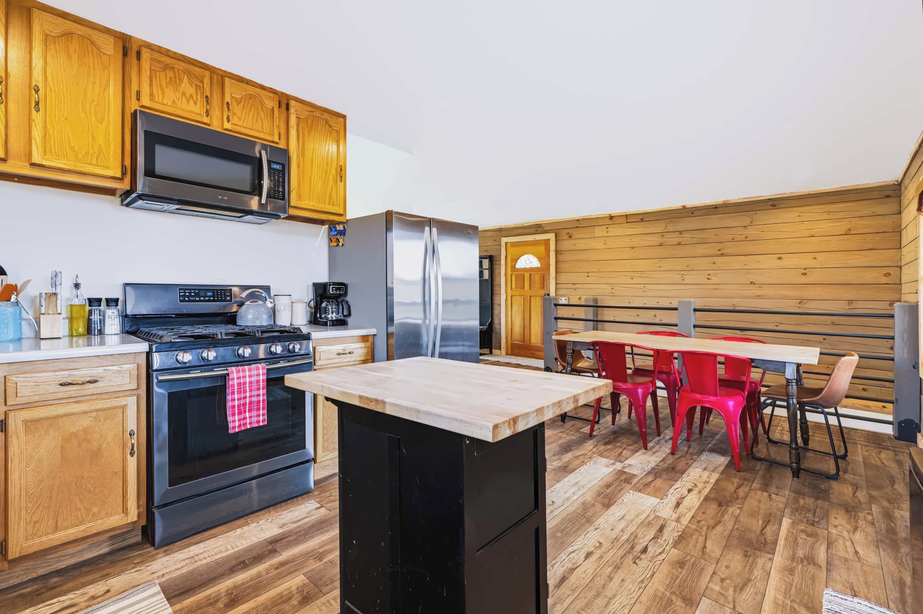 A modern kitchen with wooden cabinets, a stainless steel refrigerator, a microwave, and a stove.